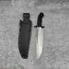 A large fixed blade bowie blade knife and its sheath lying on a grey concrete floor.