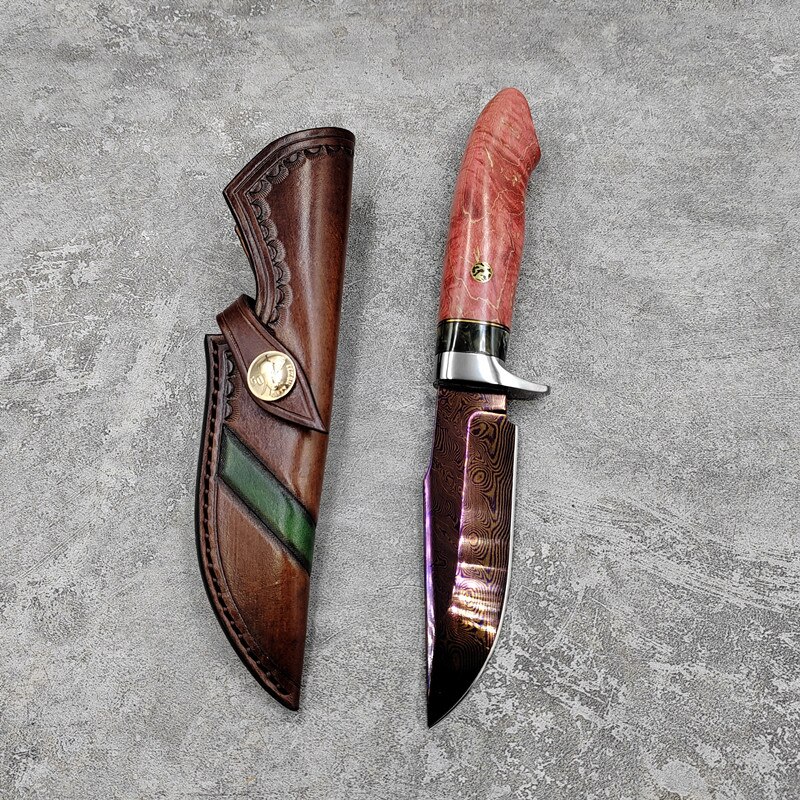 Bushcraft knives Damascus Steel bushcraft knife next to its leather sheath, lying on a grey concrete floor.